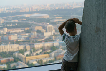 Boy looking through the window. He is on the high floor of Moscow City building. This is modern business skyscrapers of Moscow