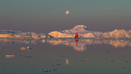 Greenland midnight Sunrise mirror panorama with moon on red sail ship	