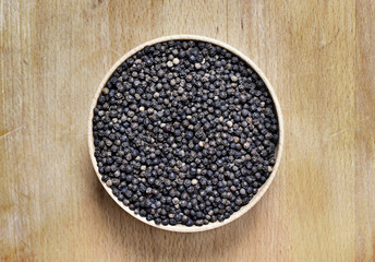 Black peppercorns and milled pepper, arrangement in a wooden bowl. Close up shot of black pepper,...