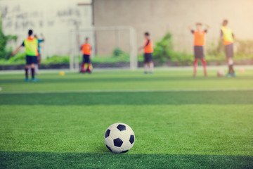 Obraz na płótnie Canvas Football on green artificial turf with blurry soccer players background.