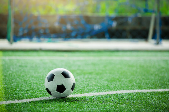 ootball on green artificial turf with blurry in front of goal.