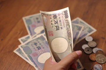 日本円(10000円札)を握る手とたくさんの紙幣	