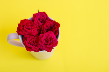 Arrangement from a cup for tea with roses on a yellow background