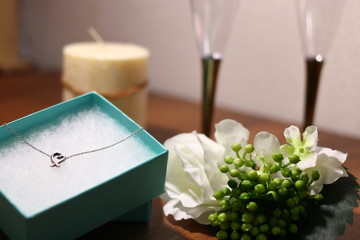 ネックレスのプレゼントとワイングラスと薔薇とキャンドル