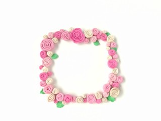 Sweet pink tone rose flower handmade from plasticine clay arrange as a frame are beautiful on white background, cute floral dough