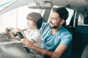Man With Son Are Sitting At The Wheel Of New Car.