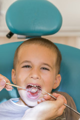 Dentist examining little boy's teeth in clinic. Close up of boy having his teeth examined by a dentist. A child at the dental clinic. With the doctors. vertical photo