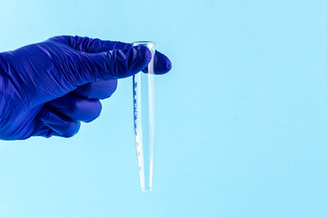 Laboratory test tubes in the hands of a lab technician on a blue background. Laboratory analysis...