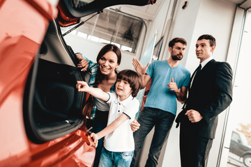 Young Family Are Choosing A New Car In Showroom.