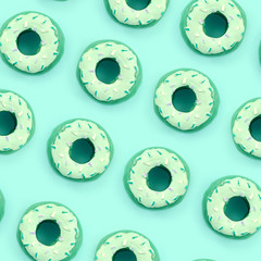 Many small plastic donuts lies on a pastel colorful background. Flat lay minimal pattern. Top view