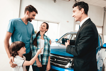 Obraz premium Young Family Are Choosing A New Car In Showroom.