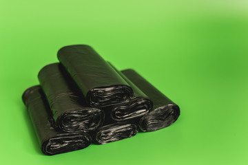 New black rolls of garbage bags against a green background