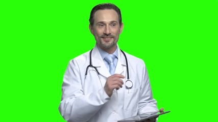 Handsome friendly male doctor with tablet. Portrait of positive doctor talking. Green screen hromakey background for keying.