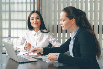 Women looking financial documents in laptop at table