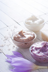 beauty product samples and autumn crocus herbal flower on white wooden table