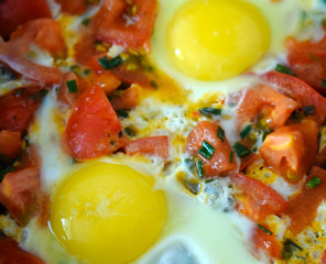 Egg with tomatoes, green onions and cheese. Glass of steamed milk. White plate on black background. Rich protein Breakfast. Food for athletes. Diet menu. Omelet with cheese for dinner. Slices of chees