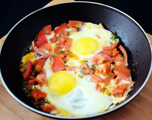 Egg with tomatoes, green onions and cheese. Glass of steamed milk. White plate on black background. Rich protein Breakfast. Food for athletes. Diet menu. Omelet with cheese for dinner. Slices of chees