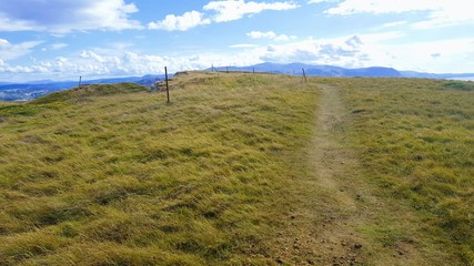 Dirt path off to the side, up a beautiful,grassy hill in Wales