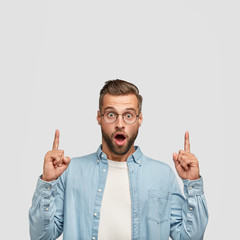 Vertical portrait of handsome unshaven young hipster, stares at camera with bugged eyes, keeps jaw...