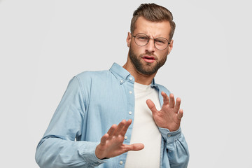 Oh no, dont bother me about this question. Displeased European man makes refusal gesture, keeps hands in front, feels aversion, says its forbidden, dressed in casual clothes, isolated on white