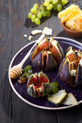 Gourmet appetizer of figs with goat cheese,walnuts and honey on ceramic plate and brown wooden background, traditional Turkish dessert