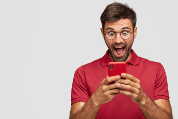 Photo of amazed European blogger holds modern cell phone, recieves unexpected message from...