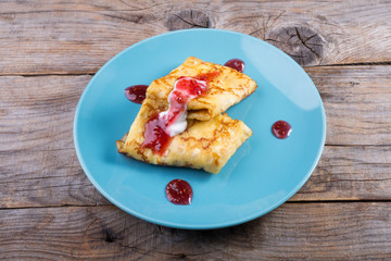 Pancakes served with cream and red jam