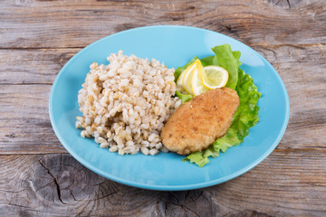 Pearl barley porridge served with fish cutlet