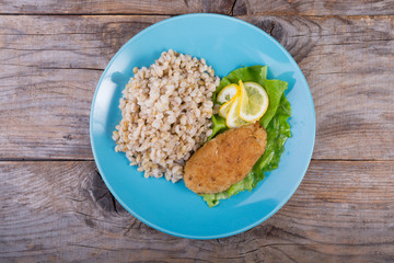 Pearl barley porridge served with fish cutlet