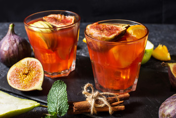 Cocktail fruit sangria with apples, orange, figs, grapes on stone table