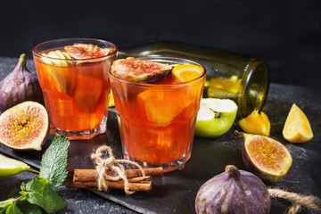 Cocktail fruit sangria with apples, orange, figs, grapes on stone table