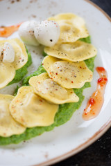 Close-up of ravioli on a bedding of green peas puree, vertical shot, selective focus