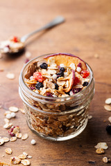 Granola, muesli in glass jar. Healthy breakfast. Organic oats with apples, berries, nuts. Copy space