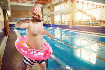 A funny fat man with a beard swims in the swimming pool.