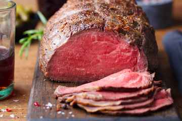 Roast beef on cutting board. Wooden background. Close up.