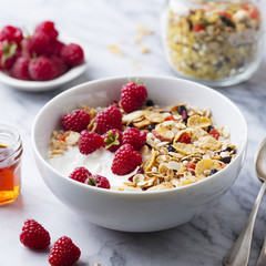 Healthy breakfast. Fresh granola, muesli with yogurt and berries on marble background.