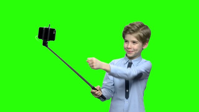 Boy with selfie stick showing fig on camera. Green hromakey background for keying.