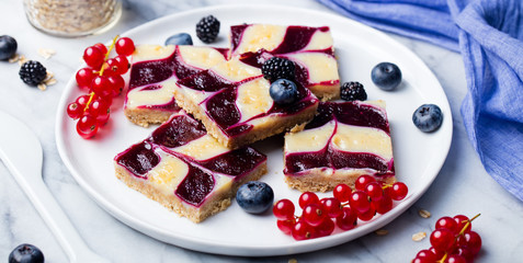 Oatmeal, oat bars with fresh berries on a white plate. Marble background. Healthy breakfast.