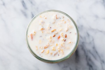 Overnight oats in glass jar on marble table. Top view.