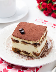 Tiramisu, traditional Italian dessert on a white plate. Close up.