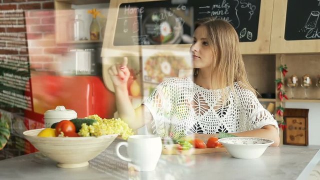 Pretty blonde woman uses futuristic hologram panel interface, preapring salad with video instruction from online web page