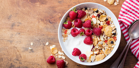 Healthy breakfast. Fresh granola, muesli with yogurt and berries on wooden background.