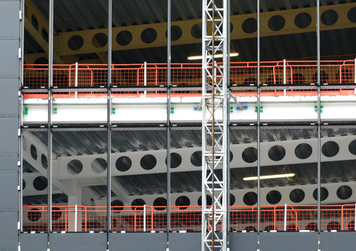 detail of the construction site of a metal framed large building development with a hoist running up the outside and safety fencing with structural steel girders and floors visible