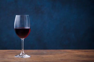 Glass of red wine on wooden table. Blue background. Copy space.