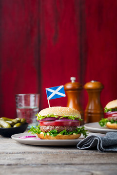 Burger on a plate with pickles. Wooden background. Copy space.
