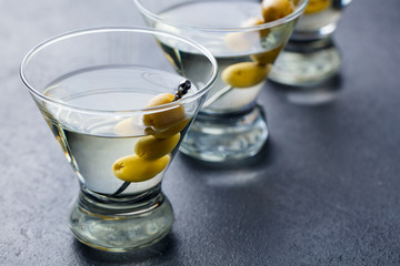 Martini cocktail with green olives. Slate background. Close up.