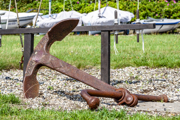 Rusty anchor lying on the green meadow and stones © Lukassek