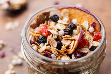 Granola, muesli in glass jar. Healthy breakfast. Organic oats with apples, berries and nuts.