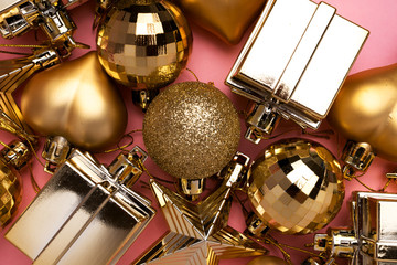 Golden Christmas decoration toys on pink background. Merry Christmas and Happy New Year. Top view. Place for text