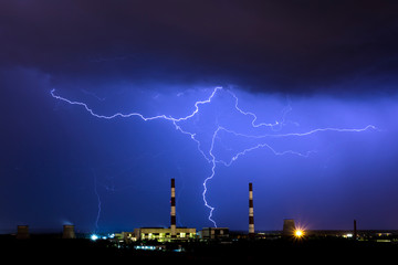 The cooling towers of thermal power station in the rainy night during the storm with the lightning